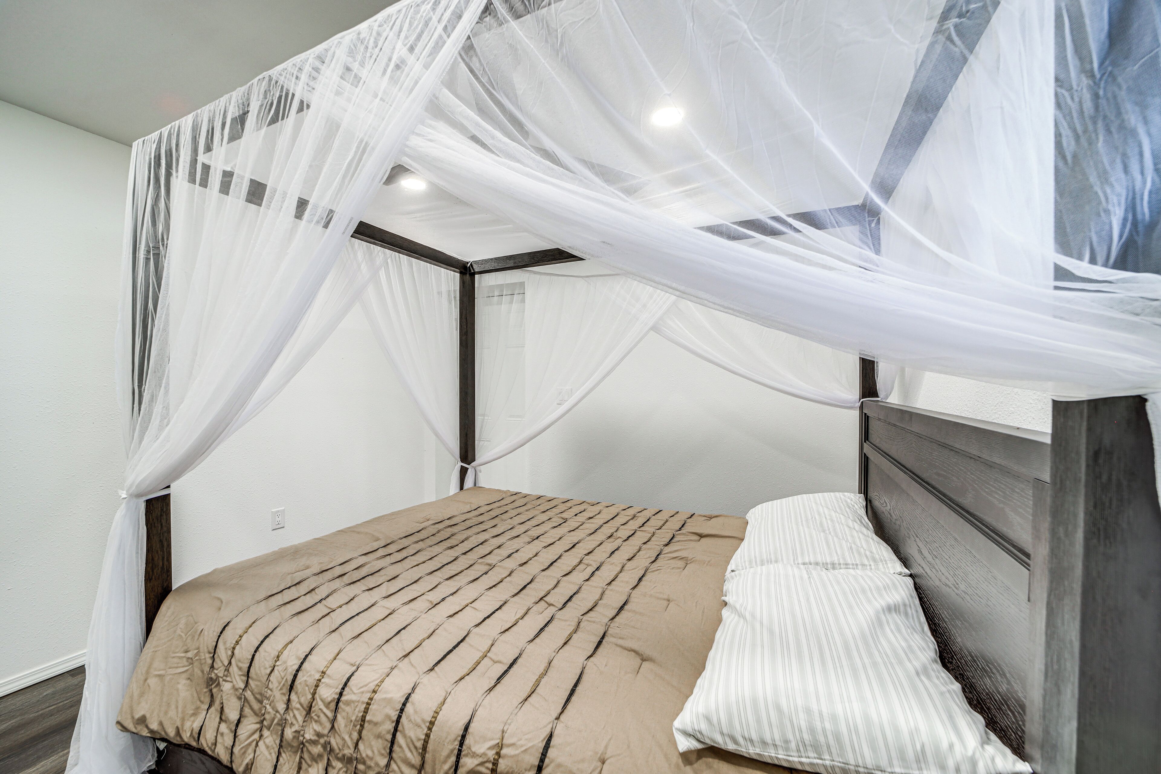 A bed with a canopy, a wooden headboard, and a striped pillow.