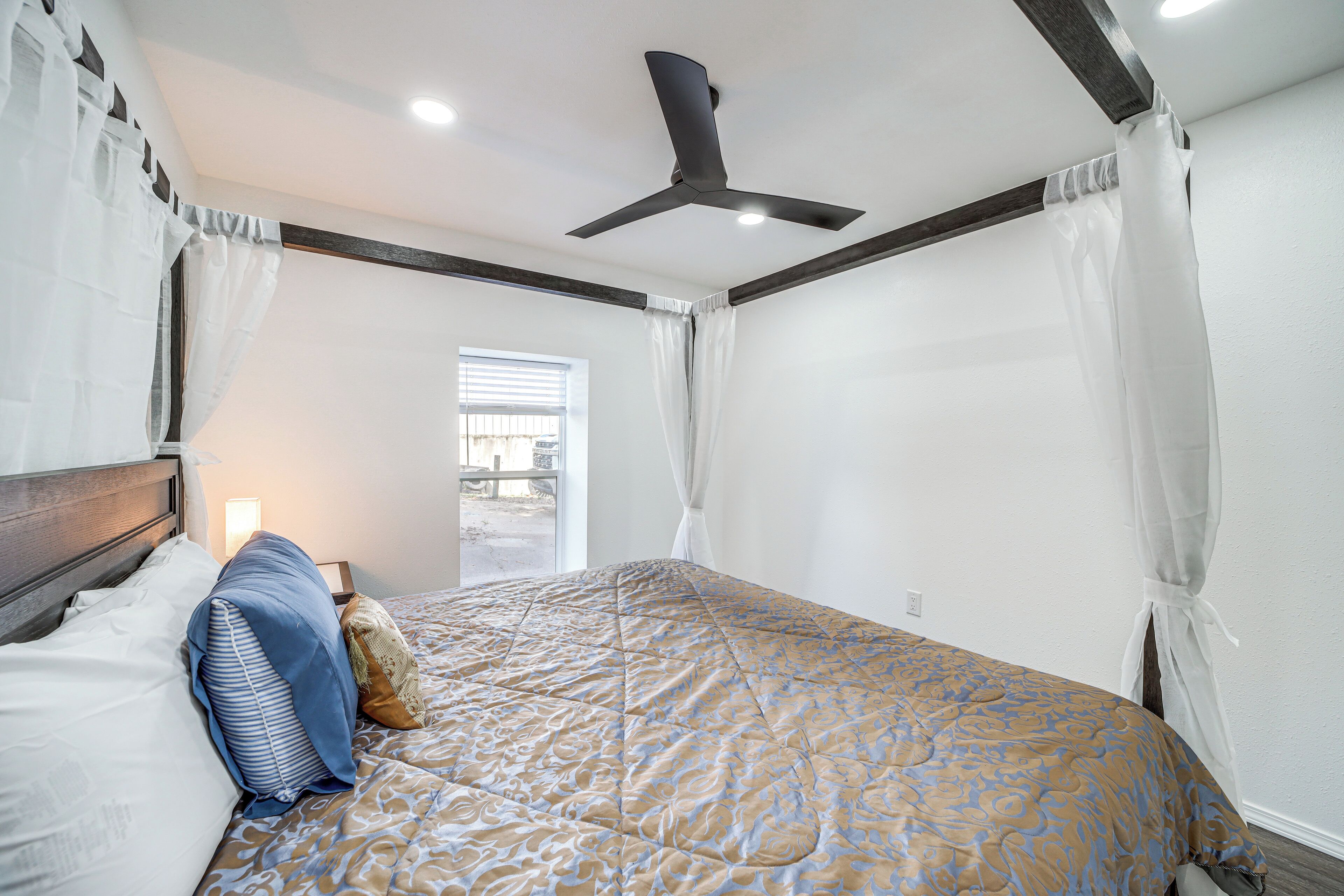 A bedroom with a bed, a ceiling fan, and a window with curtains.