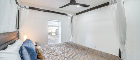 A bedroom with a bed, a ceiling fan, and a window with curtains.