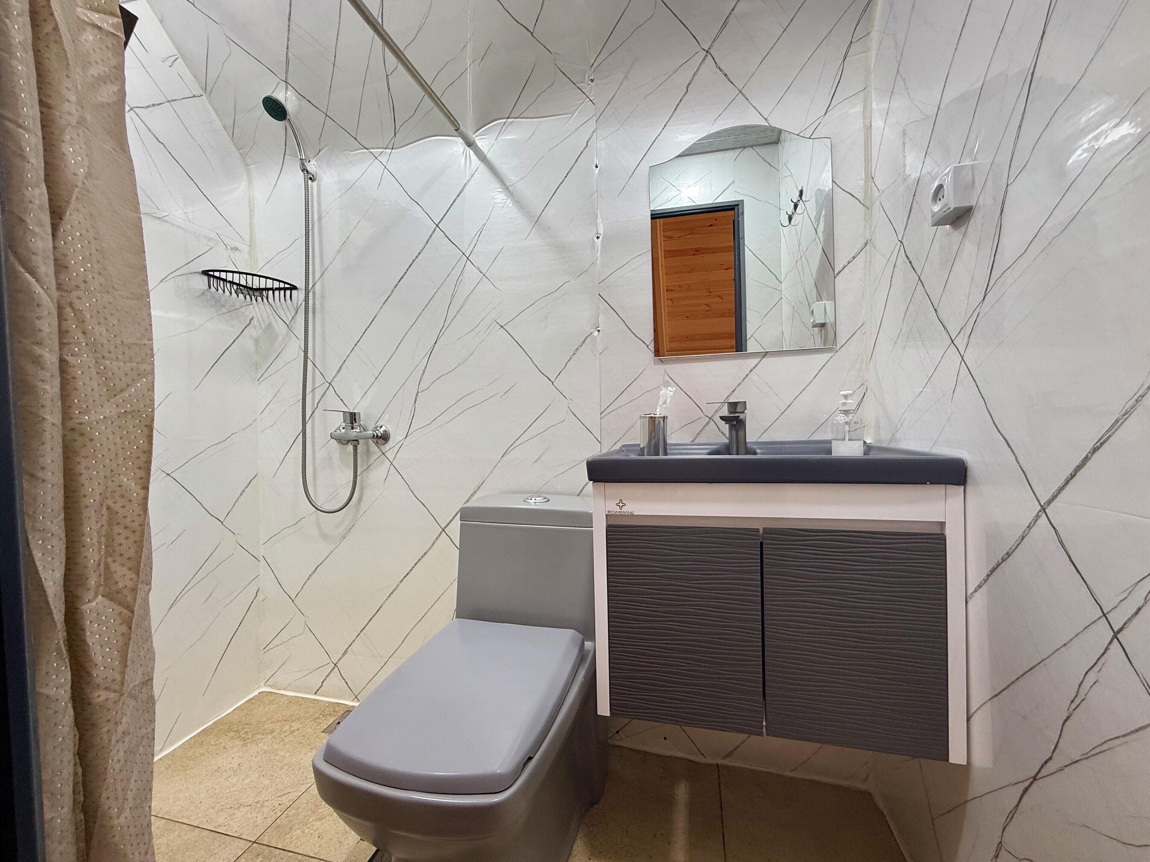 A bathroom with a shower, toilet, and sink.