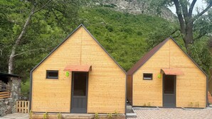 Two wooden cabins with numbered doors, a paved area, and a few ducks.