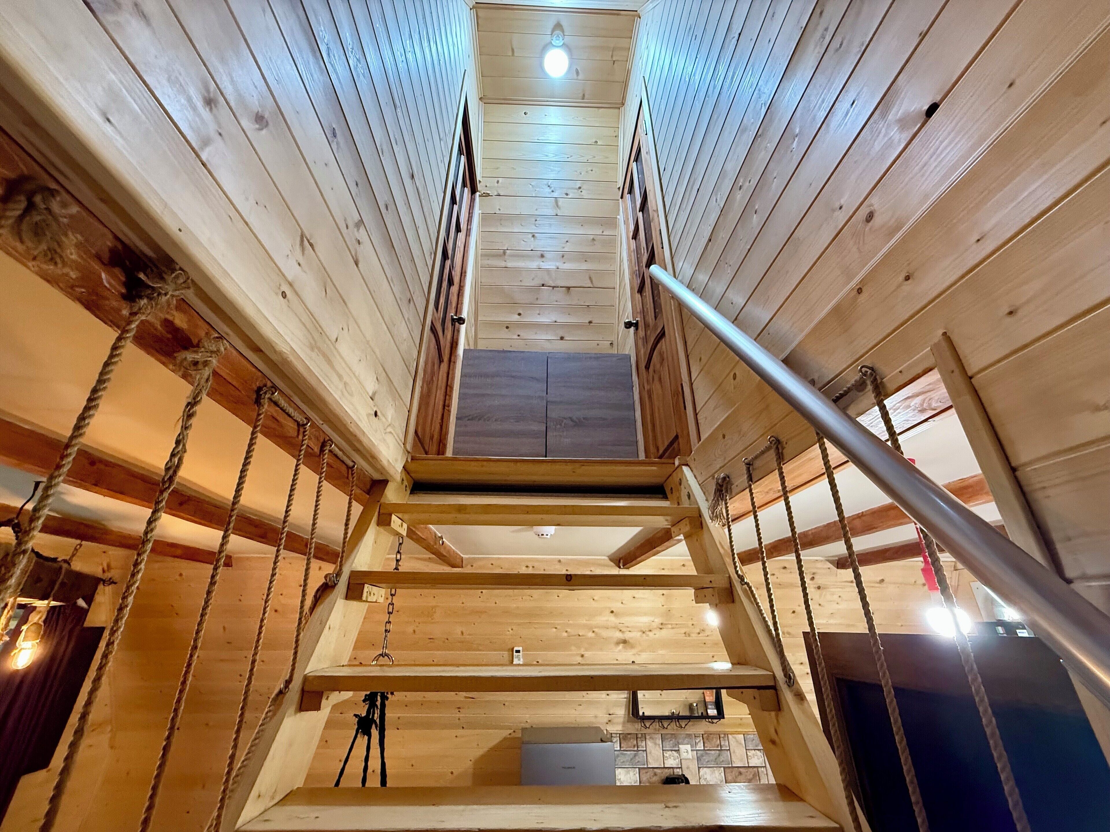 Un escalier en bois avec une rampe métallique, menant à un étage supérieur du bâtiment.
