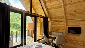 A wooden cabin room with a bed, a table, and chairs.