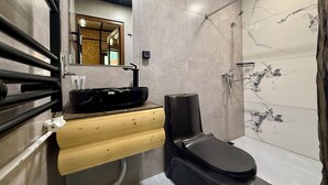 A modern bathroom with a black sink, wooden vanity, and a toilet.