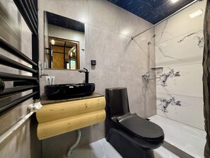 A modern bathroom with a black sink, wooden vanity, and a toilet.