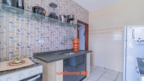A compact kitchen with a gas stove, a coffee machine, and a water dispenser. - Apartamento em Ubatuba com Churrasqueira (Ubatuba)