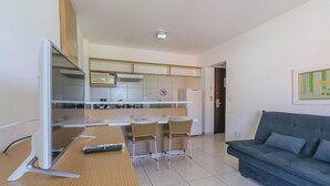 A modern living room with a grey sofa and a dining area with a kitchen in the background.