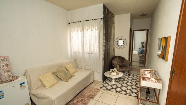 Una sala de estar con un sofá, una mesa de centro, un tapete estampado y una zona de comedor con una mesa y sillas.