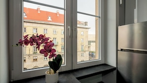Una cucina con frigorifero integrato, una finestra con un'orchidea in vaso e vista sugli edifici.