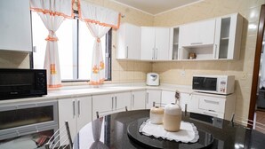 Une cuisine avec des meubles blancs, un four à micro-ondes, un grille-pain et une machine à café.