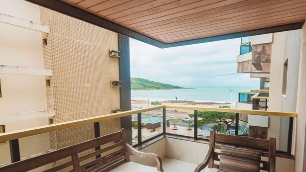 A balcony with a view of the sea, a tiled wall, and a wooden ceiling.