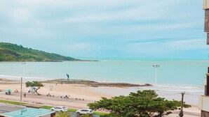 A coastal view with a beach, a sculpture, and a road with vehicles.
