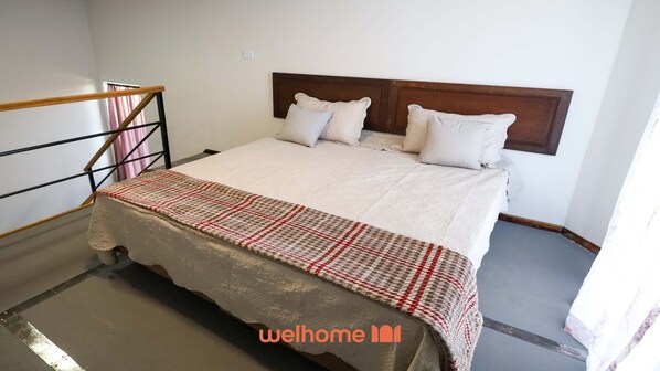 A bedroom with a bed, a headboard, and a bedside table.