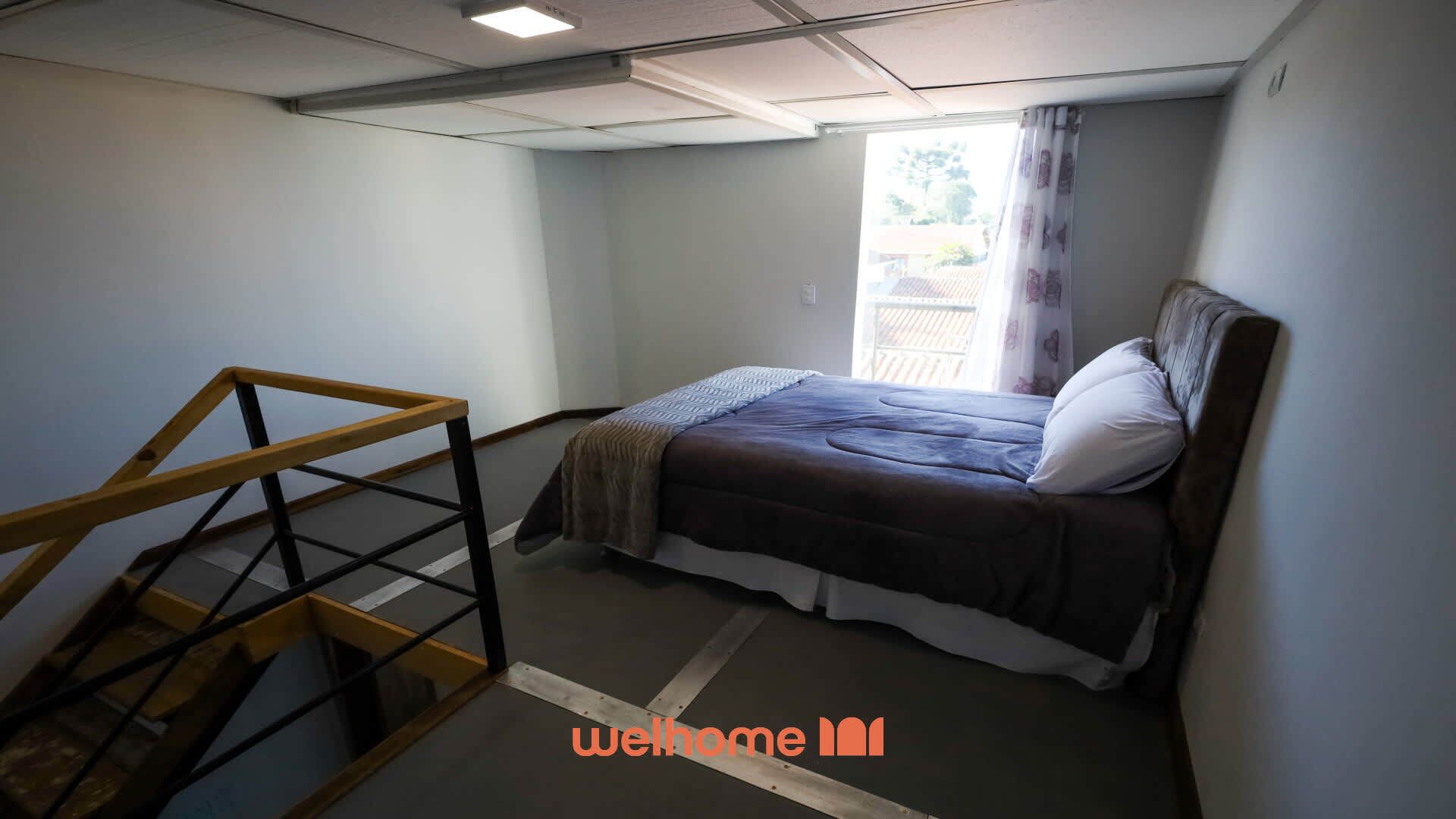 Une petite chambre à coucher avec un lit, une échelle en bois et une fenêtre avec des rideaux.