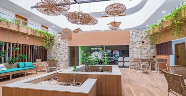 Um hall com mobiliário de vime, paredes de pedra, luminárias de vime suspensas e plantas.