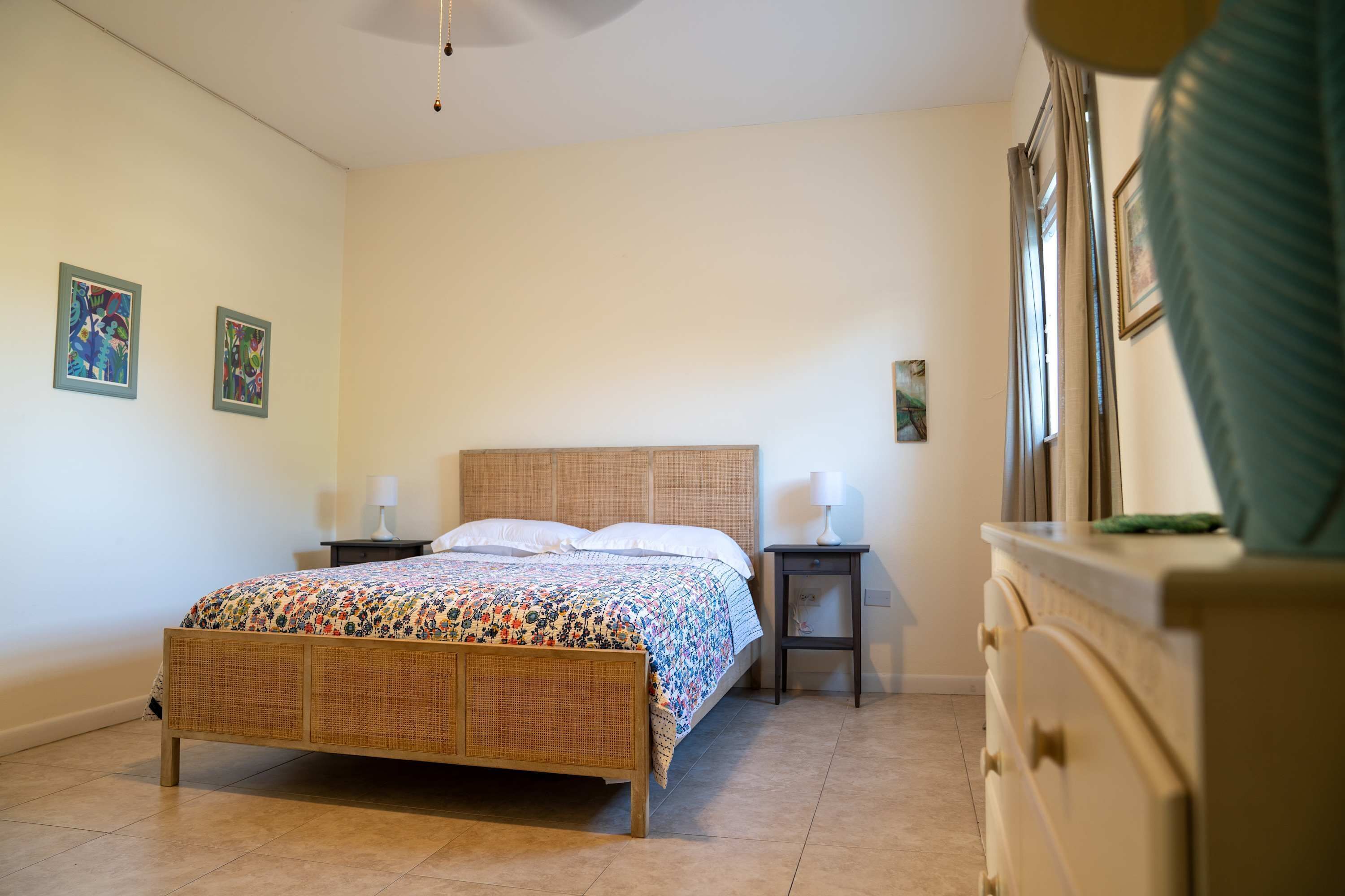 A bedroom with a bed, bedside tables, a dresser, and a window with curtains.