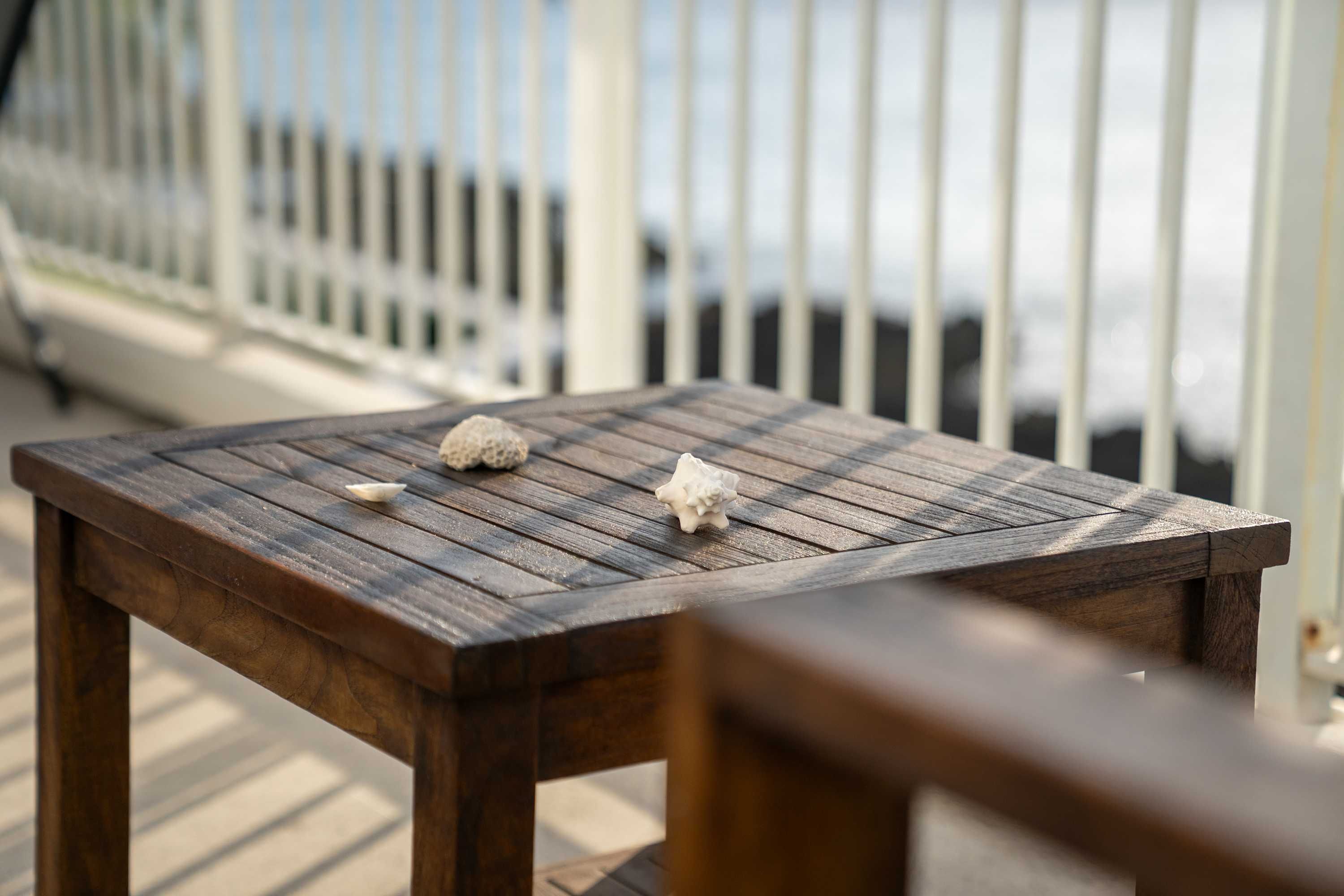 Uma mesa de madeira com dois objetos decorativos numa varanda com grade.