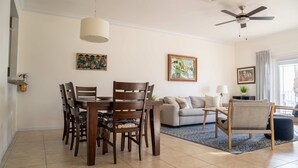 Un espace repas comprenant une table et des chaises, un ventilateur de plafond et des œuvres d’art accrochées aux murs.