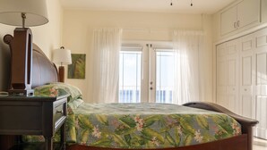 Une chambre à coucher avec un lit en bois, une table de chevet avec une lampe, une commode et une fenêtre avec des rideaux.