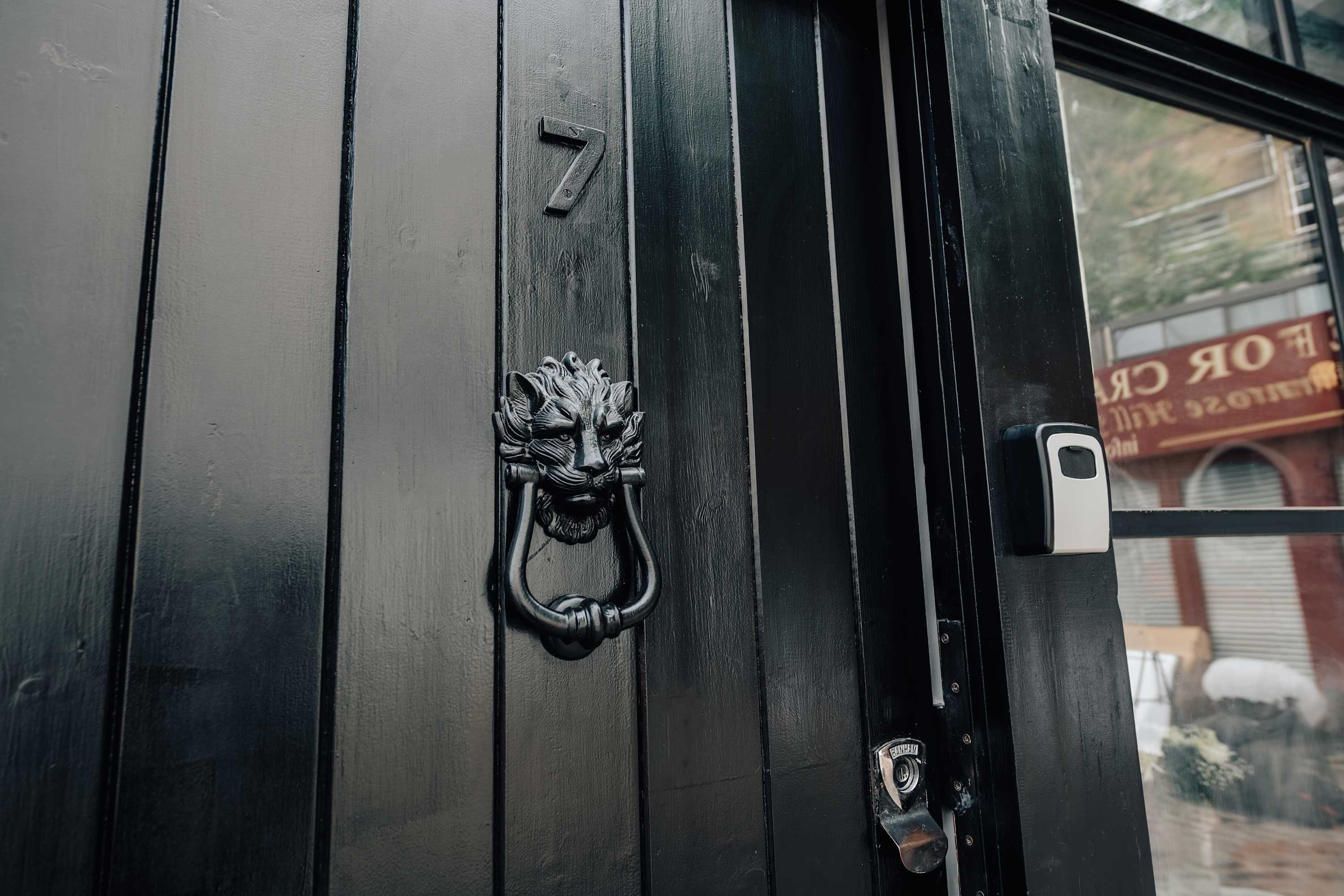 Una puerta negra con el número 7 y un llamador metálico decorativo.