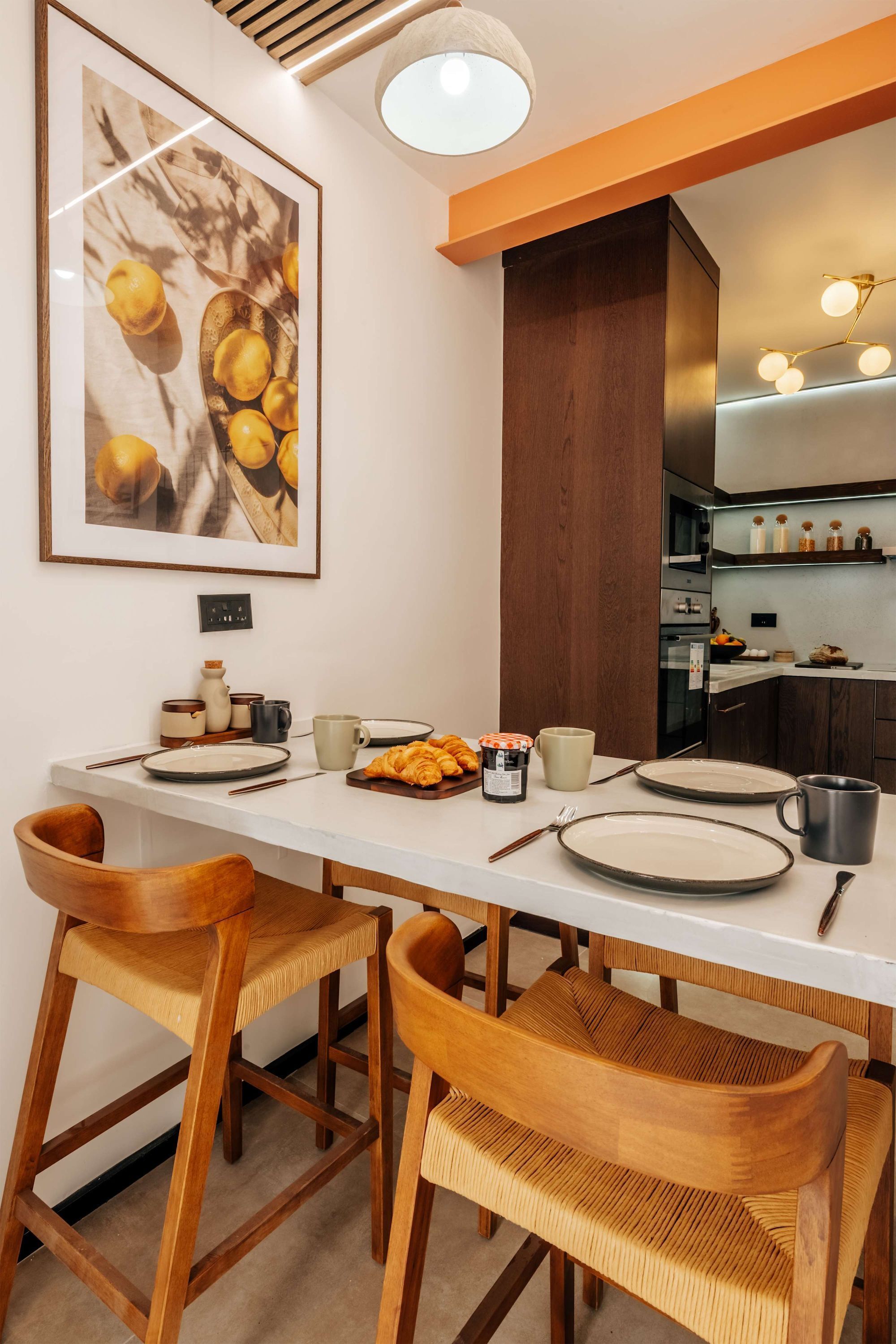 Zona pranzo con tavolo bianco, sedie in legno e un quadro appeso alla parete.