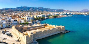 A coastal city with a prominent historical fortification, a marina with boats, and a backdrop of mountains. - Villa Mia Peaceful Oasis in Ierapetra Crete (Ierapetra)