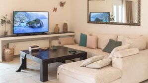 Un salon doté d’un grand téléviseur à écran plat, d’un canapé, d’une table basse et d’une cheminée.