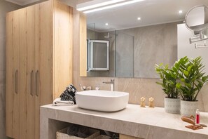 A modern bathroom with a large wooden cabinet, a white sink, and two potted plants. - Villa Mia Peaceful Oasis in Ierapetra Crete (Ierapetra)
