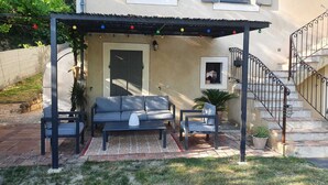 A covered patio area with a sofa, chairs, and a table, featuring a pergola with string lights. - Family villa in the luberon regional park with swimming pool for 6 people (Puget)
