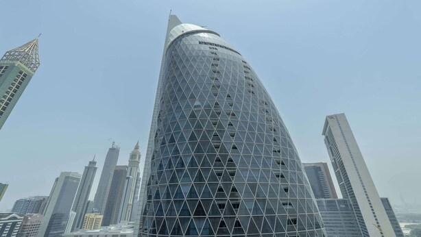 A modern skyscraper with a distinctive geometric facade and a rounded top. - StayShort - Stylish DIFC Apartment Sleeps 4 with Pool & Gym (DIFC)