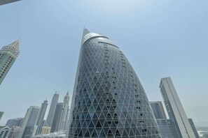 Un gratte-ciel moderne doté d’une façade géométrique originale et d’un sommet arrondi.