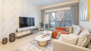 A modern living room with a large flat-screen TV, a sofa, a coffee table, and a dining area with a table and chairs. - StayShort - Stylish DIFC Apartment Sleeps 4 with Pool & Gym (DIFC)