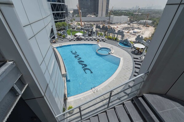 A rooftop swimming pool with a circular design and the word "JAMAC" on the water.
