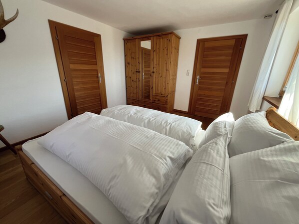 A bedroom with a bed, wooden wardrobe, and a mirror.