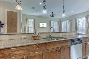 A kitchen with granite countertops, wooden cabinets, a dishwasher, and a 'Grand Welcome Austin' sign. - Charming 2BD w/Billiards, Near Lady Bird Lake & DT (Austin)