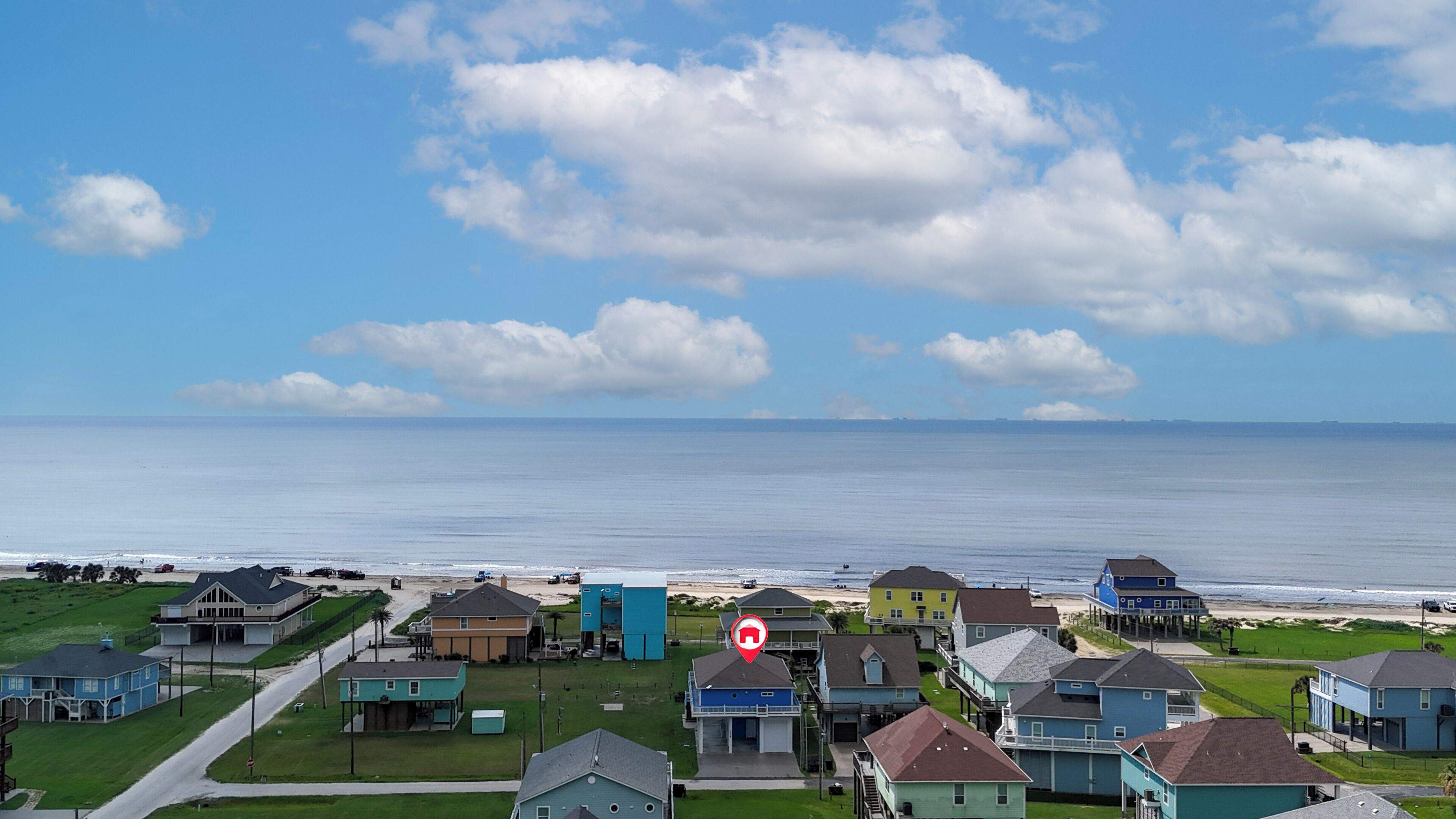 A coastal residential area with houses, a road, and a beach.