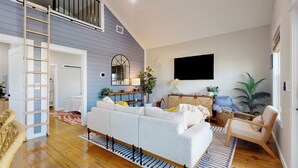 Un salon avec un canapé, un téléviseur, une échelle et un escalier.