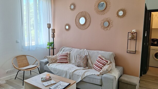 A living room with a sofa, a coffee table with books and candles, and decorative mirrors on the wall.