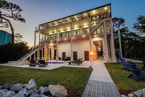 Une maison moderne à plusieurs étages, dotée d’une vaste terrasse extérieure, d’une piscine et d’une entrée bien éclairée.
