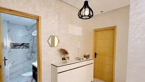 A modern bathroom with a marble floor, a white vanity, and a shower area visible through a glass door.