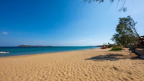 A sandy beach with a clear blue sky, a boat on the water, and a few people in the distance. - Paros Beach Studio Casa Costa Oro, 300m from Golden Beach (1BR 1BA) (Paros)