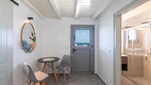 A small, modern room with a view through a door, a table with chairs, and a decorative wall piece. - Paros Beach Studio Casa Costa Oro, 300m from Golden Beach (1BR 1BA) (Paros)