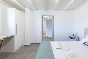 A hotel room with a bed, a desk, a chair, a nightstand, and a bathroom visible through an open door.