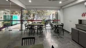 Uma área de jantar moderna com paredes de vidro, um ventilador de teto e vista para o exterior.