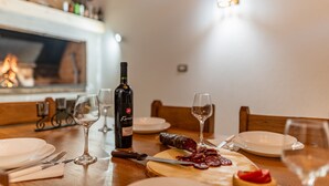 Une table à manger dressée avec des assiettes, des couverts, une bouteille de vin, des verres et une planche à découper en bois sur laquelle sont disposées des tranches de viande.