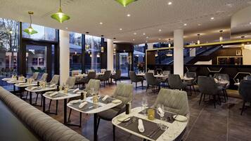 A modern restaurant with tables set for dining, a bar area, and a staircase leading to an upper level.