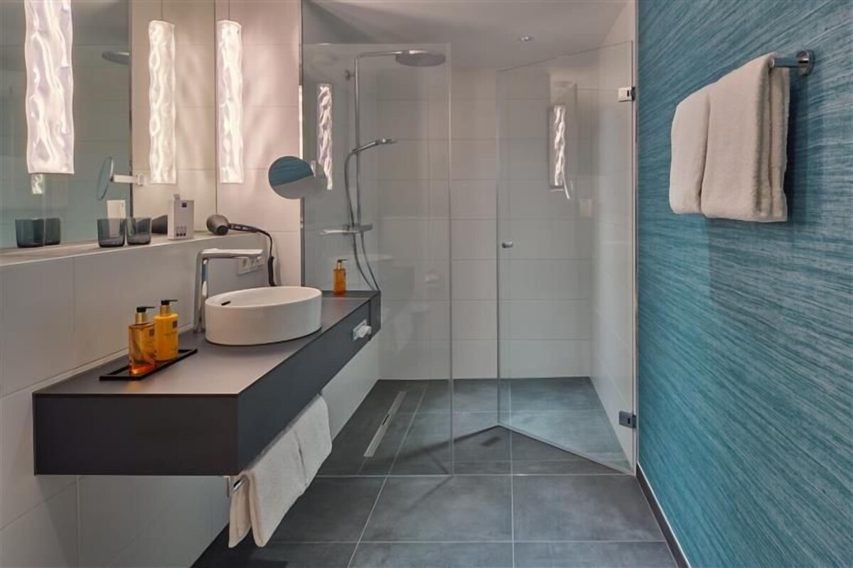Ein modernes Badezimmer mit einem runden Waschbecken, einem Spiegel und einer Duschkabine.
