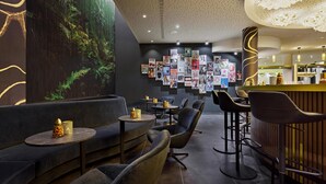Una zona relax moderna con divani, poltrone, un bar e una parete decorata con quadri incorniciati.