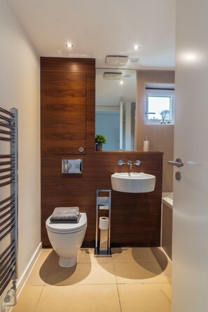 Ein modernes Badezimmer mit einem Holzlagerfläschchen, einem weißen Waschbecken und einer Toilette.