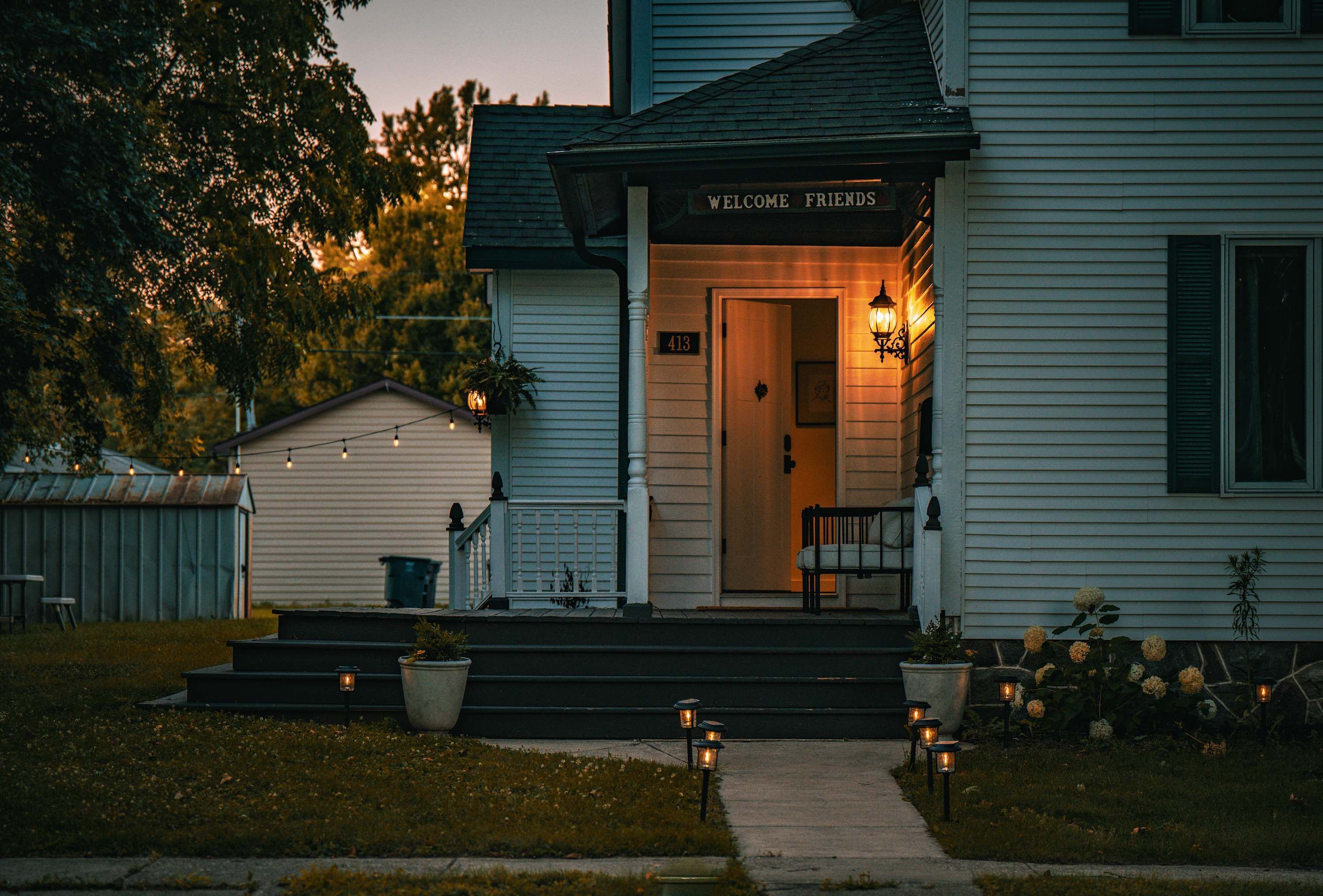A house with a porch, steps, and a 'Welcome Friends' sign.